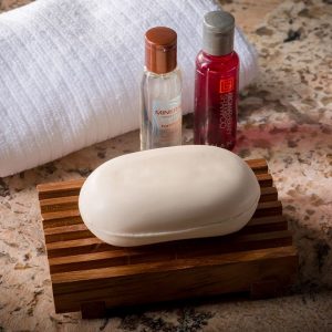 teak soap dish with shampoo bottles and towel
